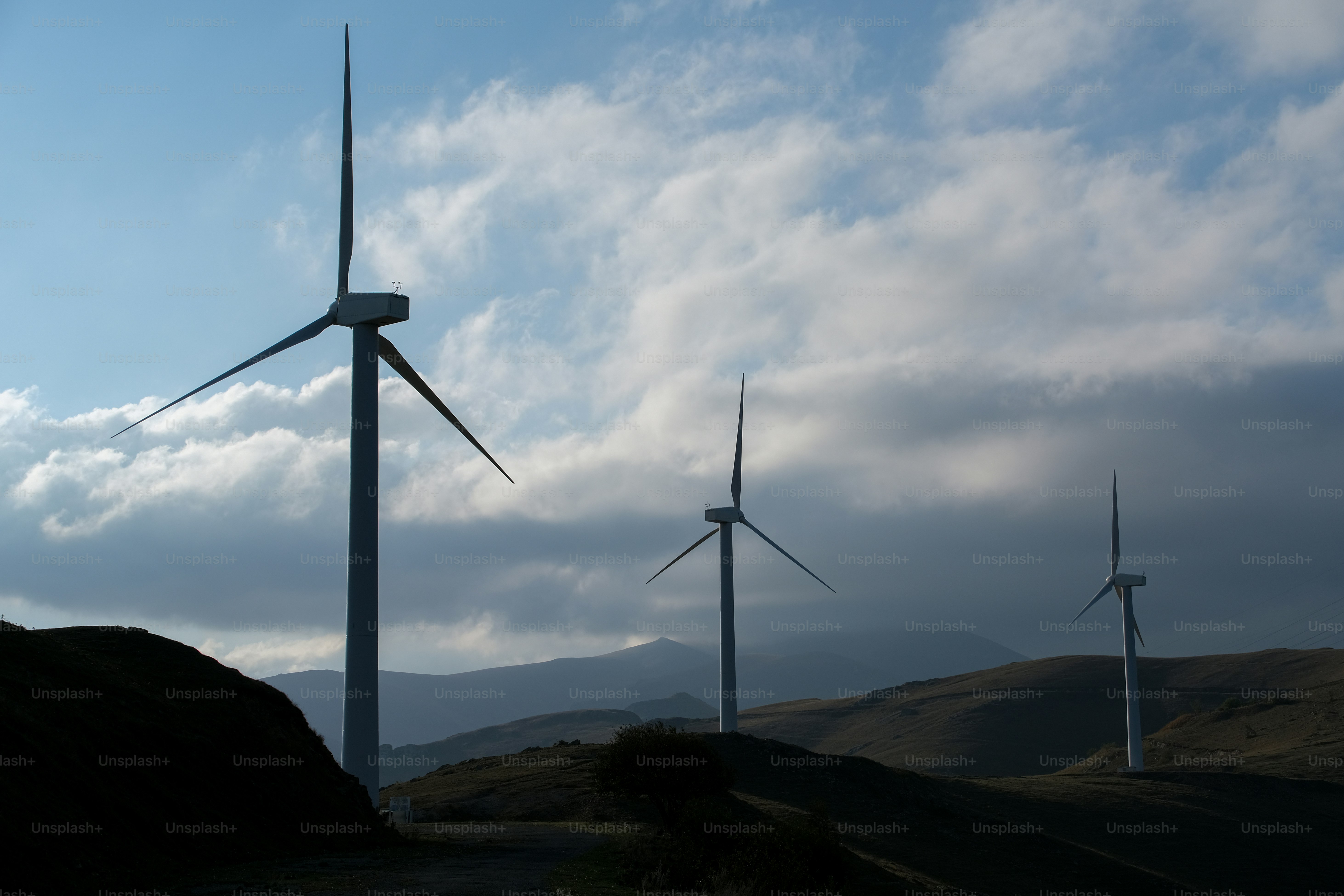 a group of windmills on a hill under a cloudy sky