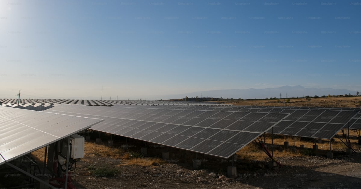 A large solar array in the middle of a field photo – Photovoltaic ...
