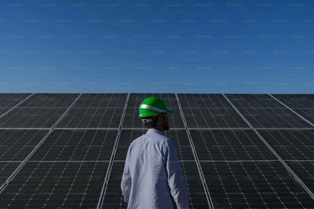 Ein Mann mit Schutzhelm, der vor einem Solarpanel steht