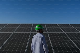 Un hombre con un casco parado frente a un panel solar