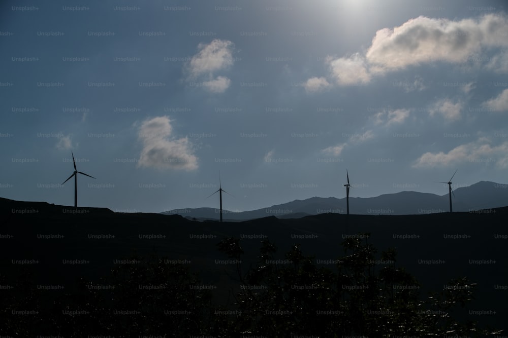 a group of windmills on a hill under a cloudy sky