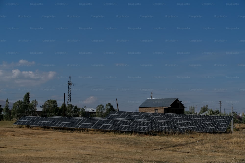 a field of solar panels with a barn in the background
