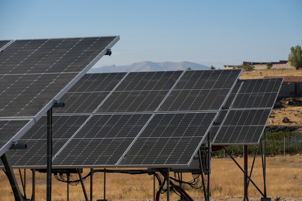 a row of solar panels sitting on top of a dry grass field