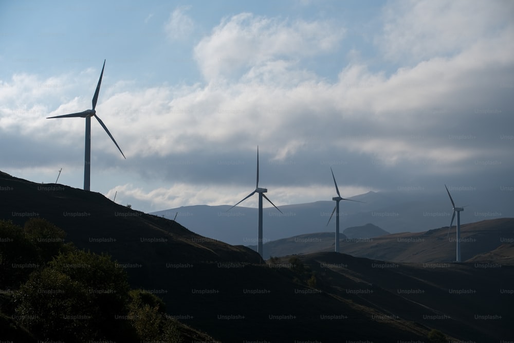 um grupo de moinhos de vento em uma colina sob um céu nublado