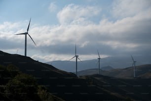 a group of windmills on a hill under a cloudy sky