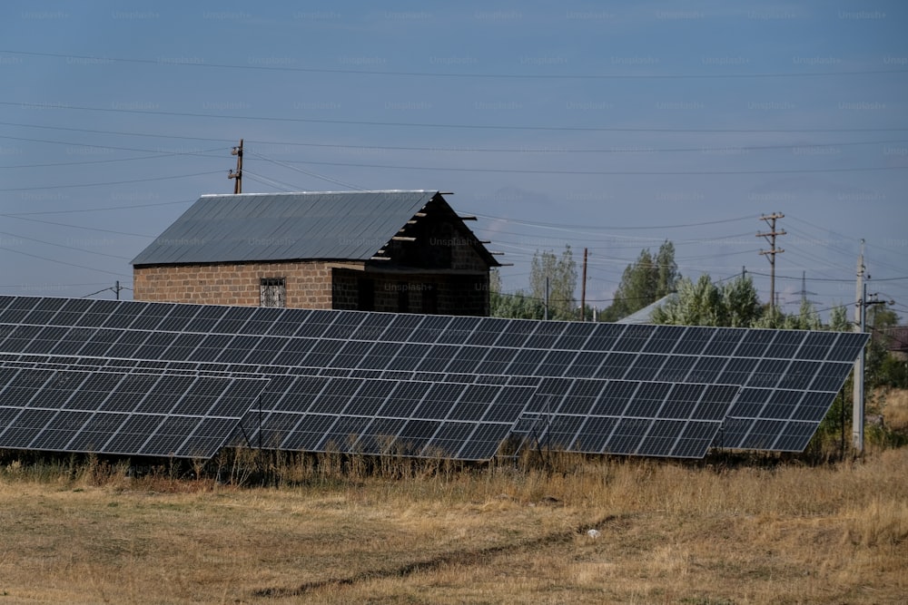 a row of solar panels in front of a barn