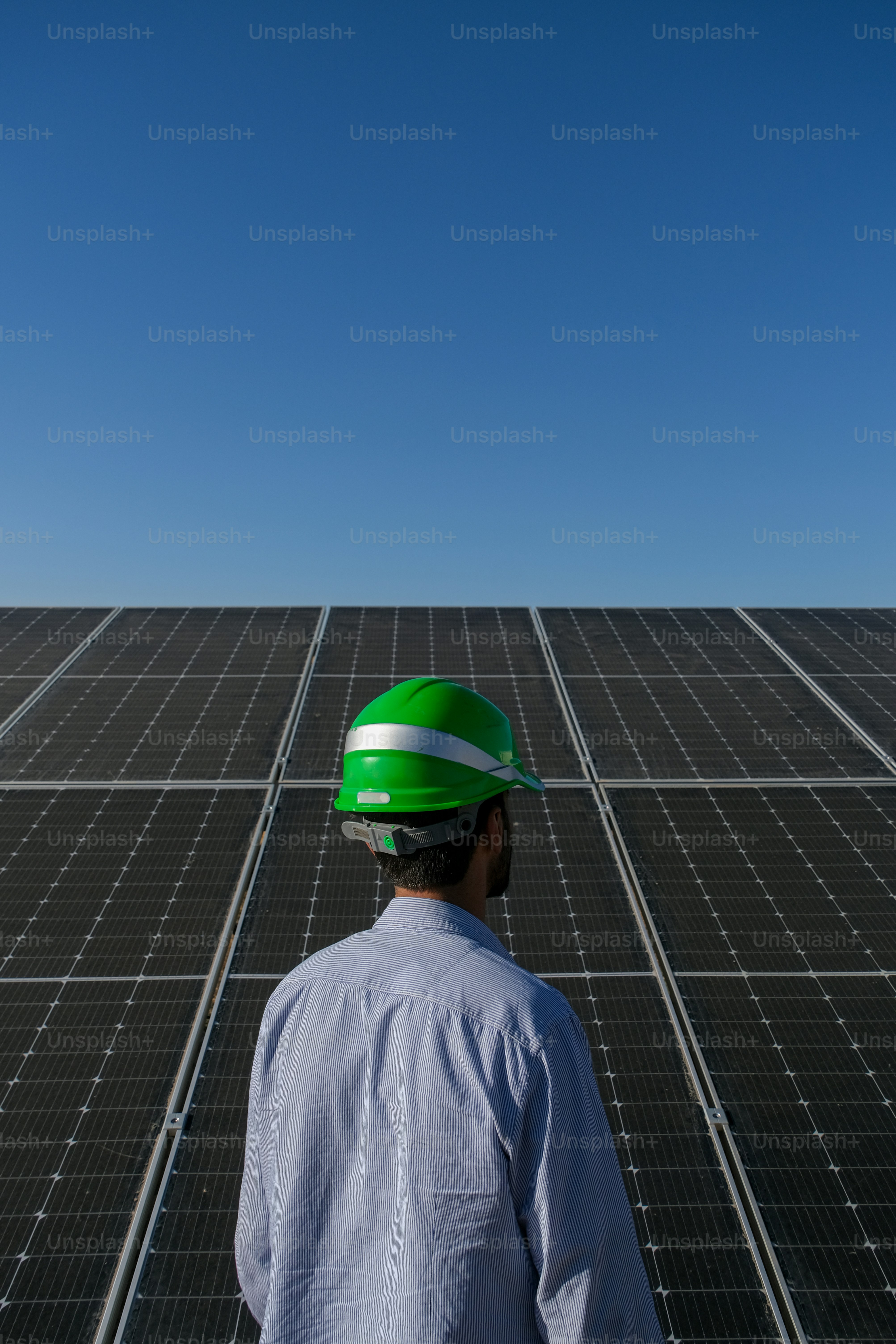 a man wearing a hard hat standing in front of a solar panel