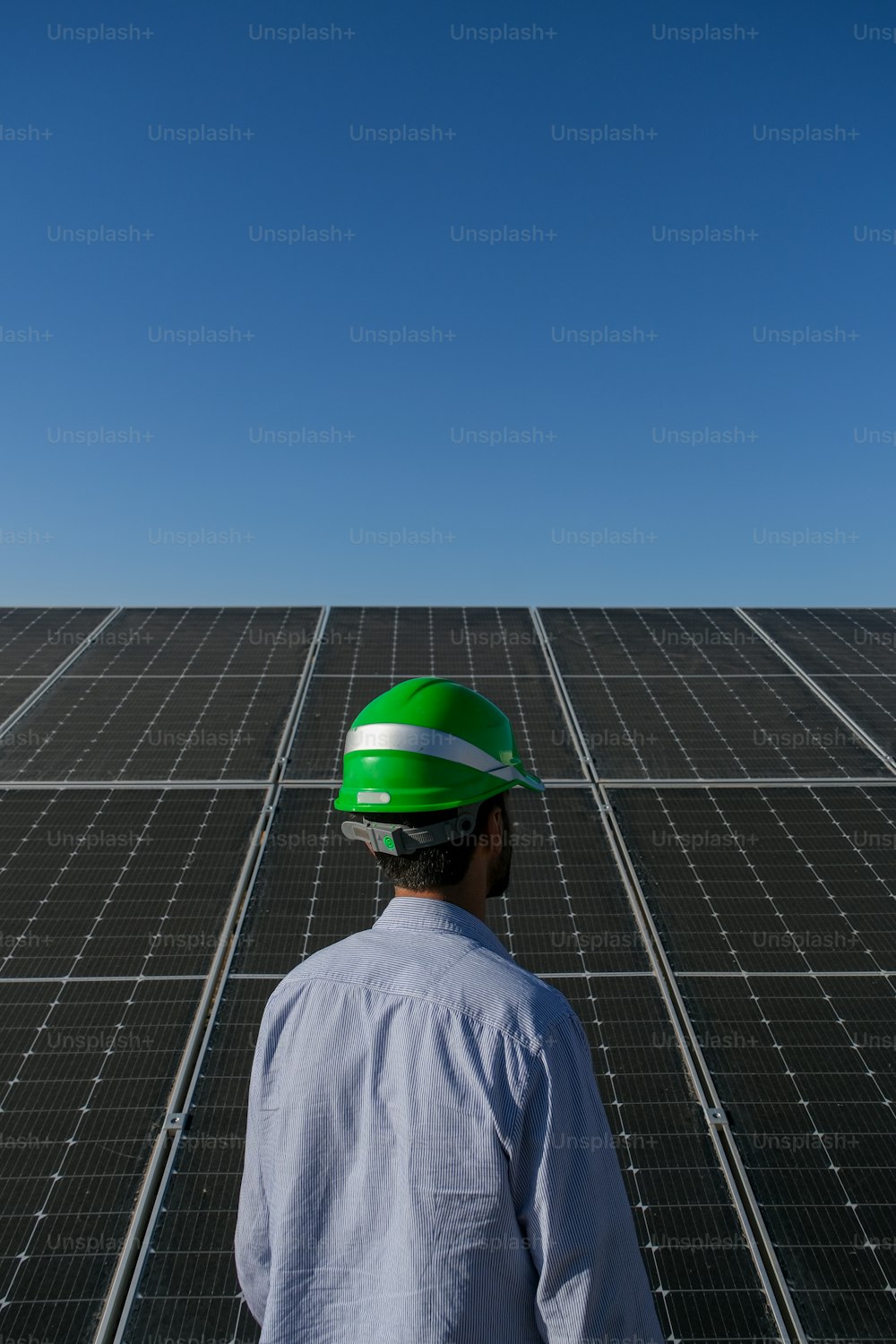 a man wearing a hard hat standing in front of a solar panel