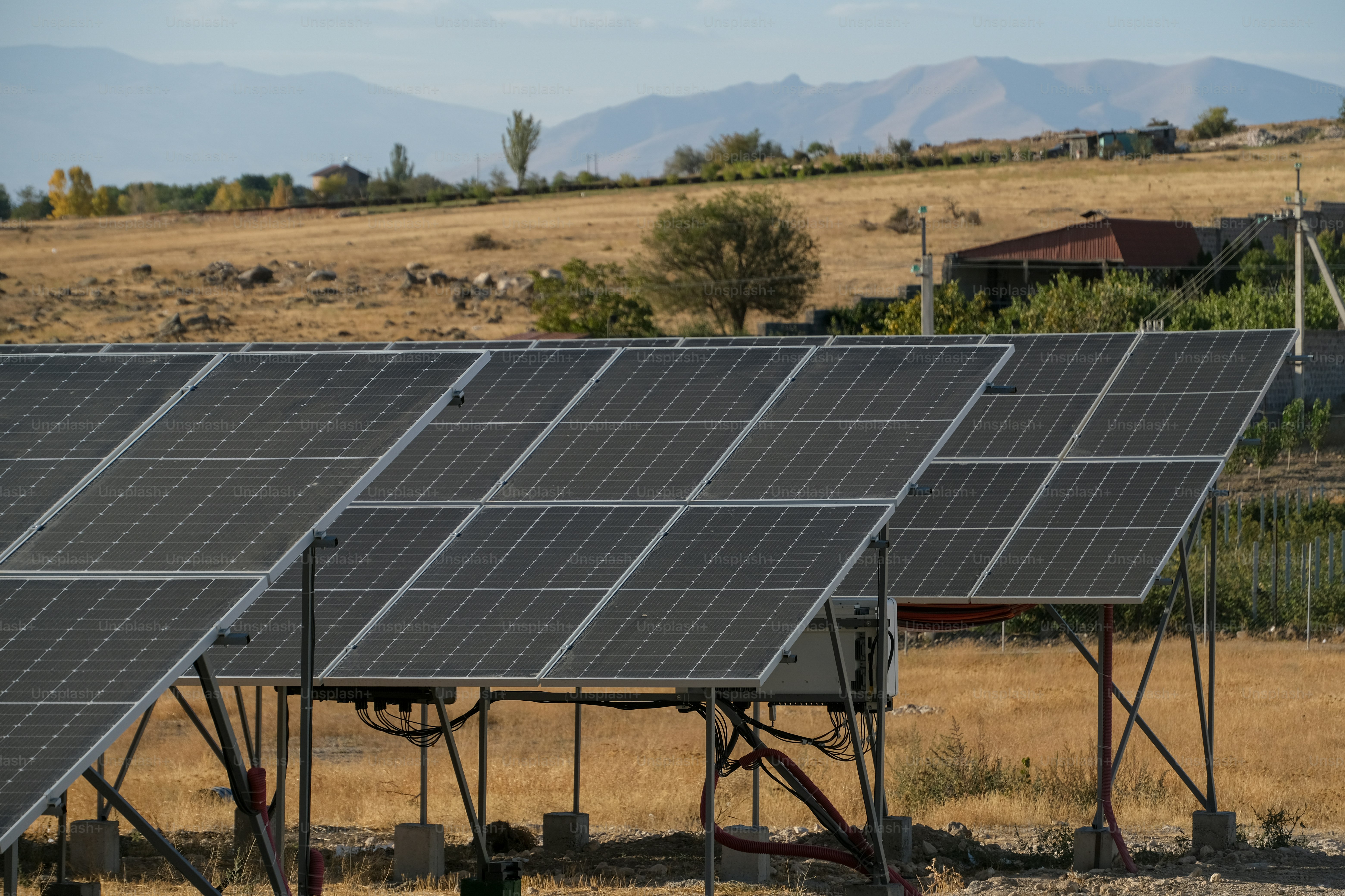 a row of solar panels sitting on top of a dry grass field