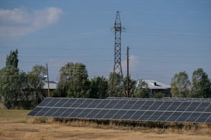 a row of solar panels in a field with power lines in the background