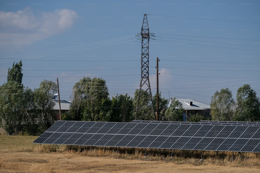 uma fileira de painéis solares em um campo com linhas de energia ao fundo