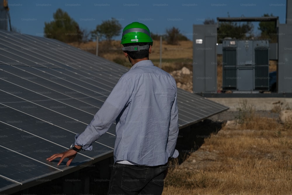a man wearing a hard hat standing next to a solar panel