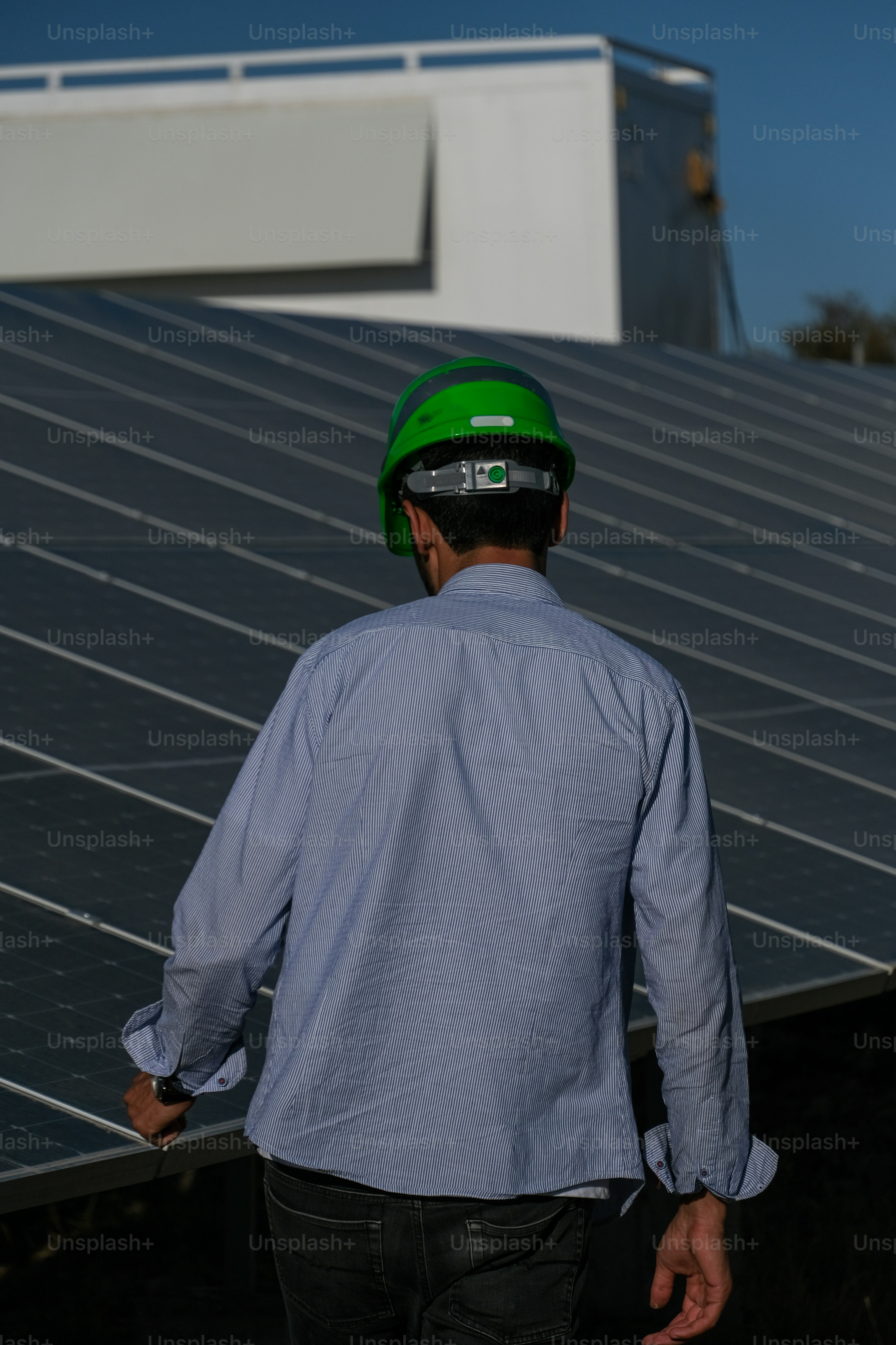 a man wearing a hard hat standing in front of a solar panel