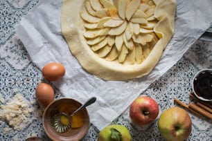 a table topped with a pie covered in apples
