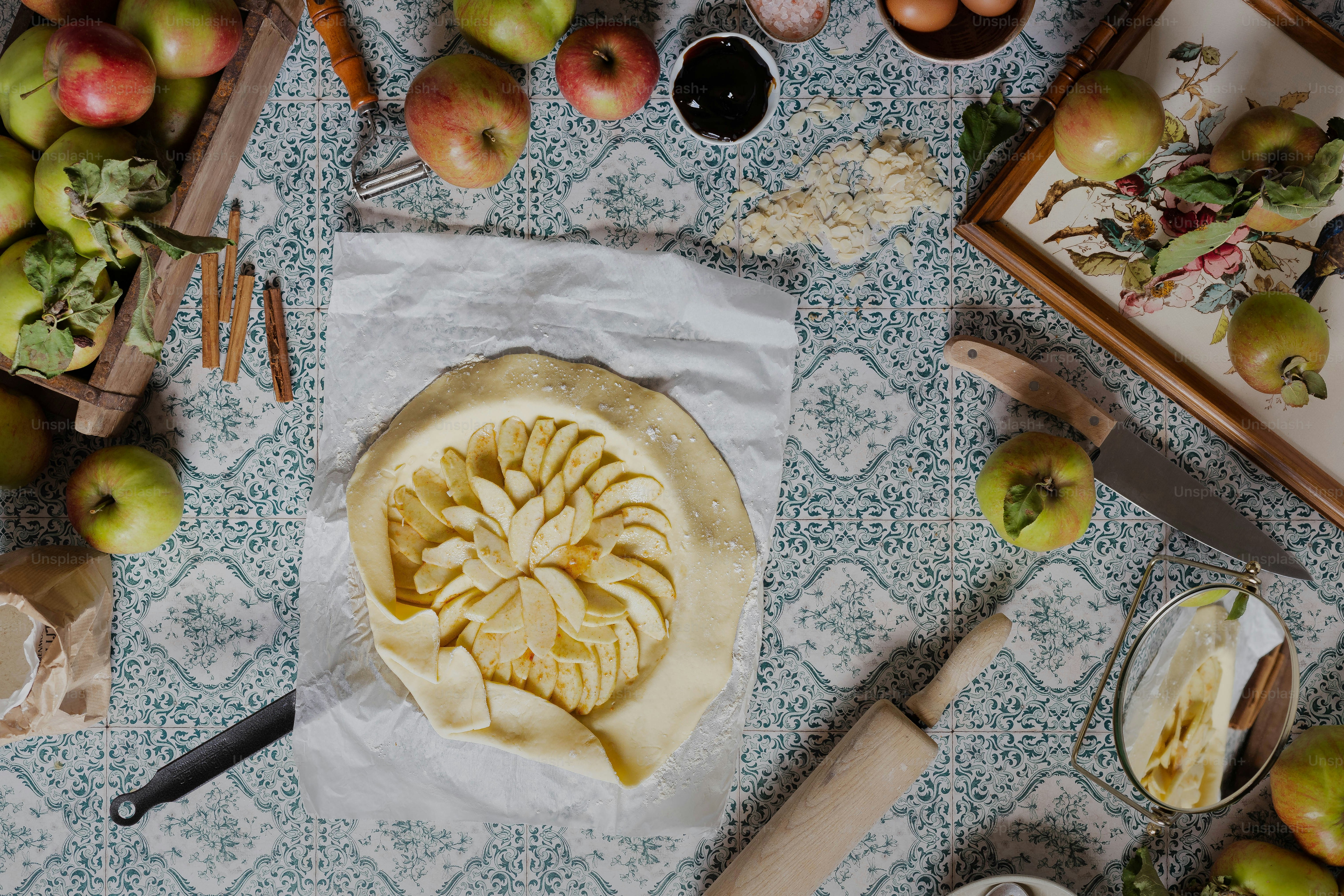 a table topped with a pie covered in sliced apples