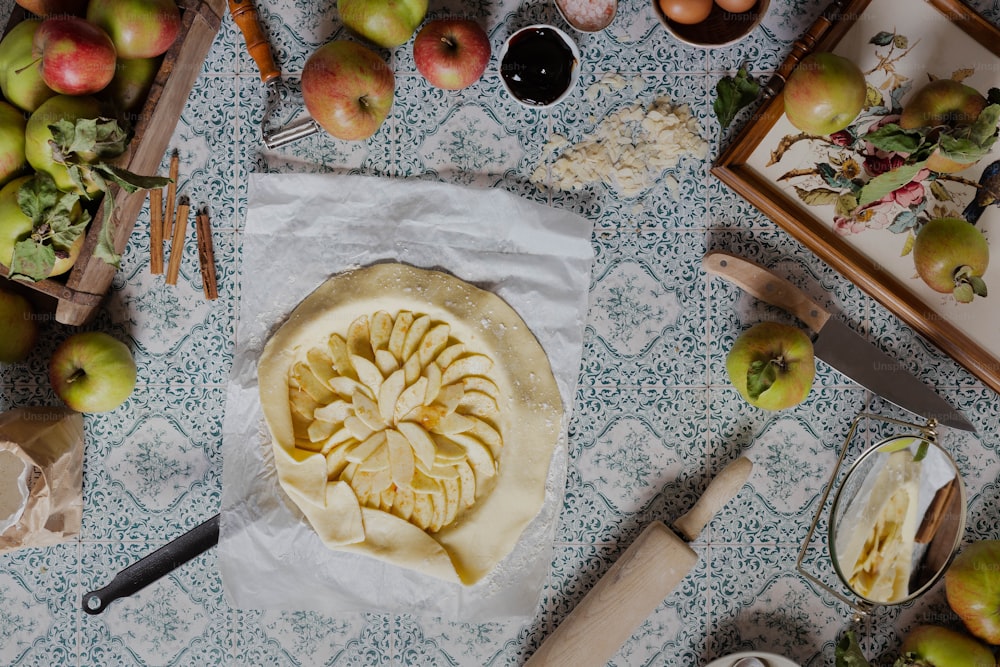 a table topped with a pie covered in sliced apples