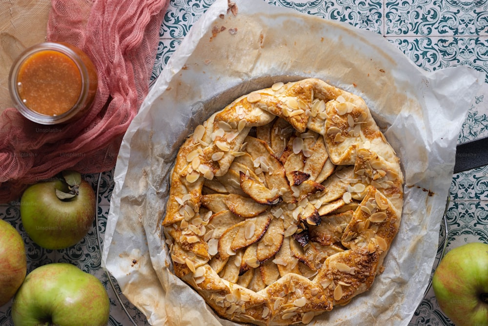 a pie sitting on top of a table next to apples