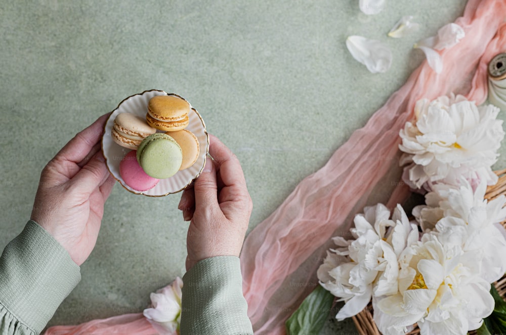 uma pessoa segurando um pequeno cupcake ao lado de uma cesta de flores