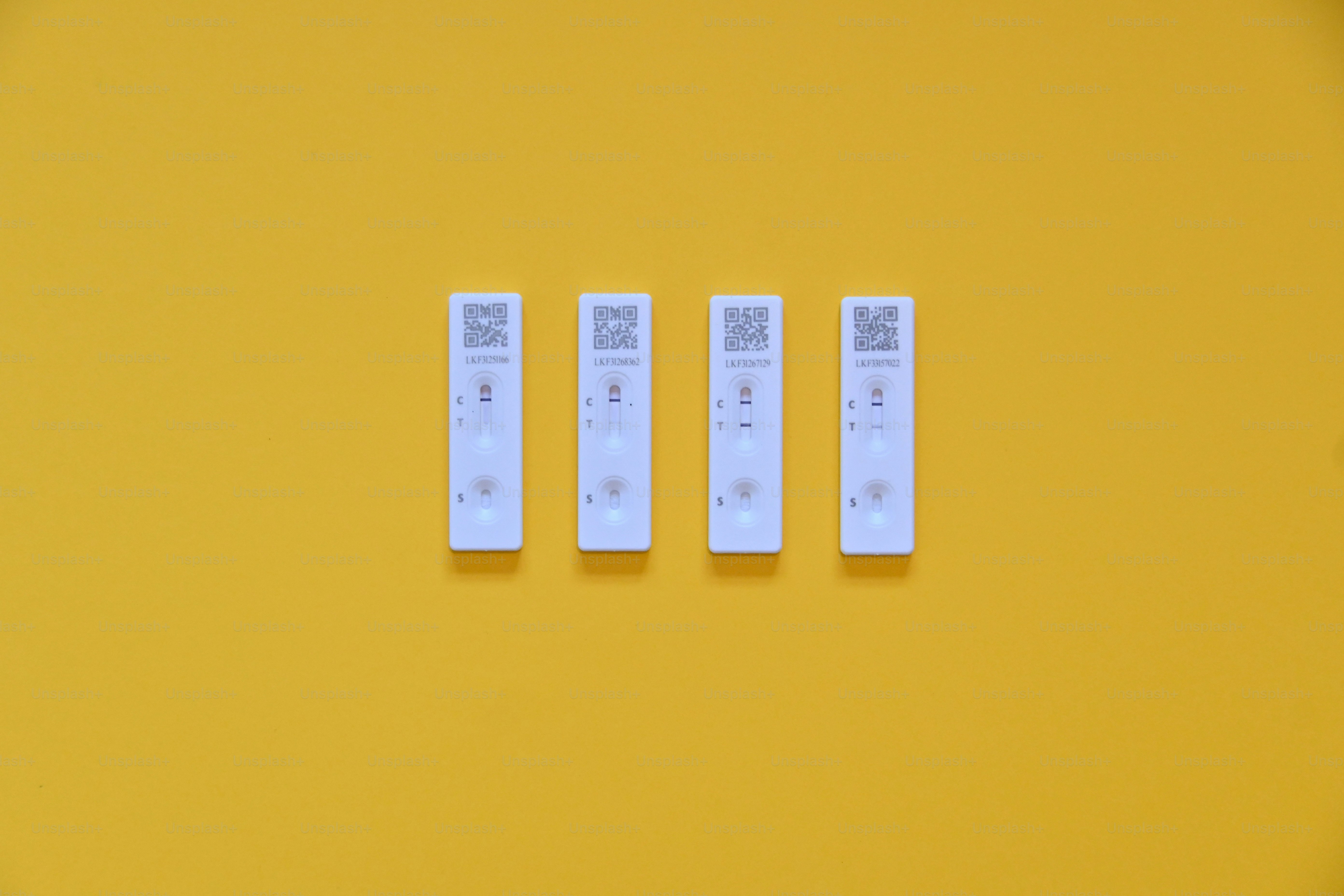 four covid 19 test results sitting on a yellow surface