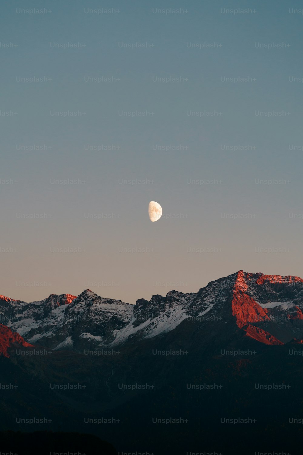 La lune se couche sur une chaîne de montagnes