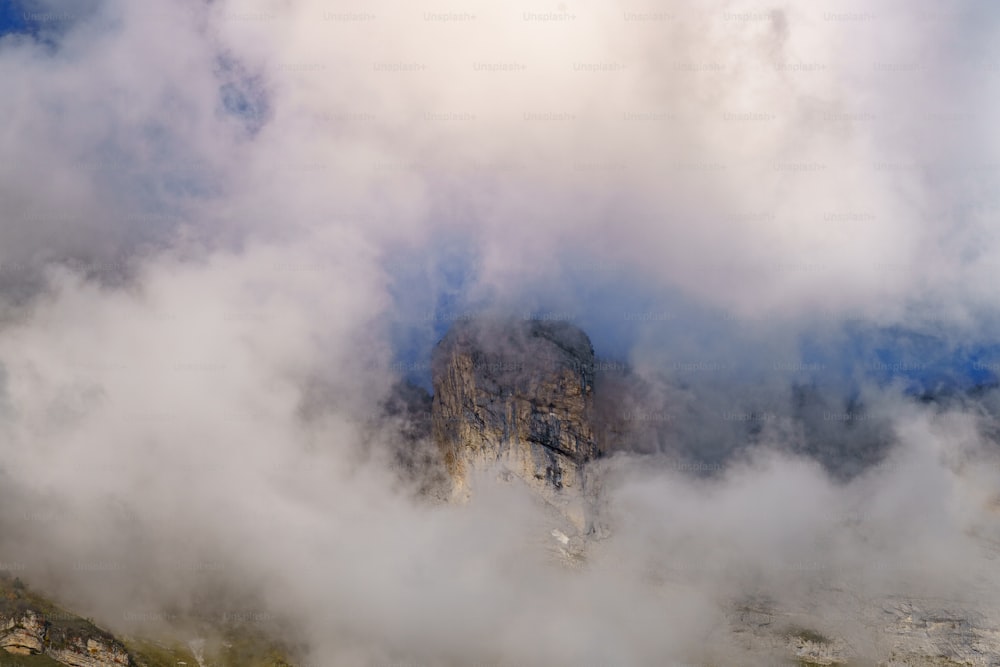 Ein in Wolken gehüllter Berg mit einem Berg im Hintergrund