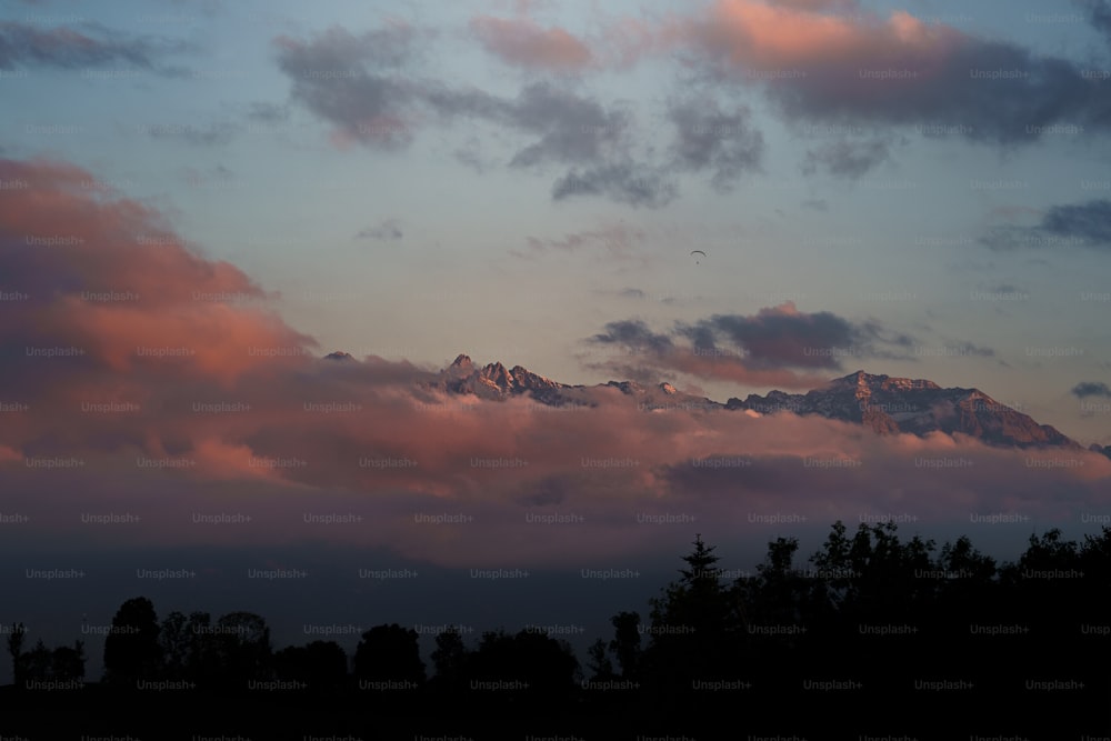 uma vista de uma montanha ao longe com nuvens em primeiro plano