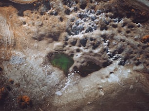 an aerial view of a green pond surrounded by rocks