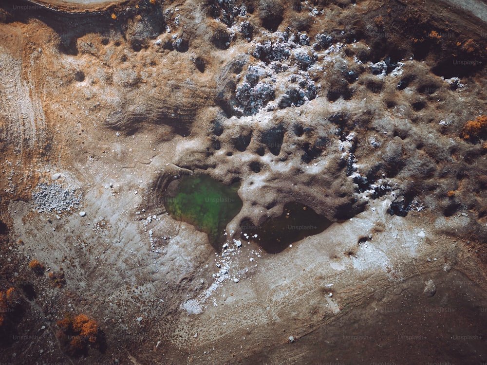 an aerial view of a green pond surrounded by rocks