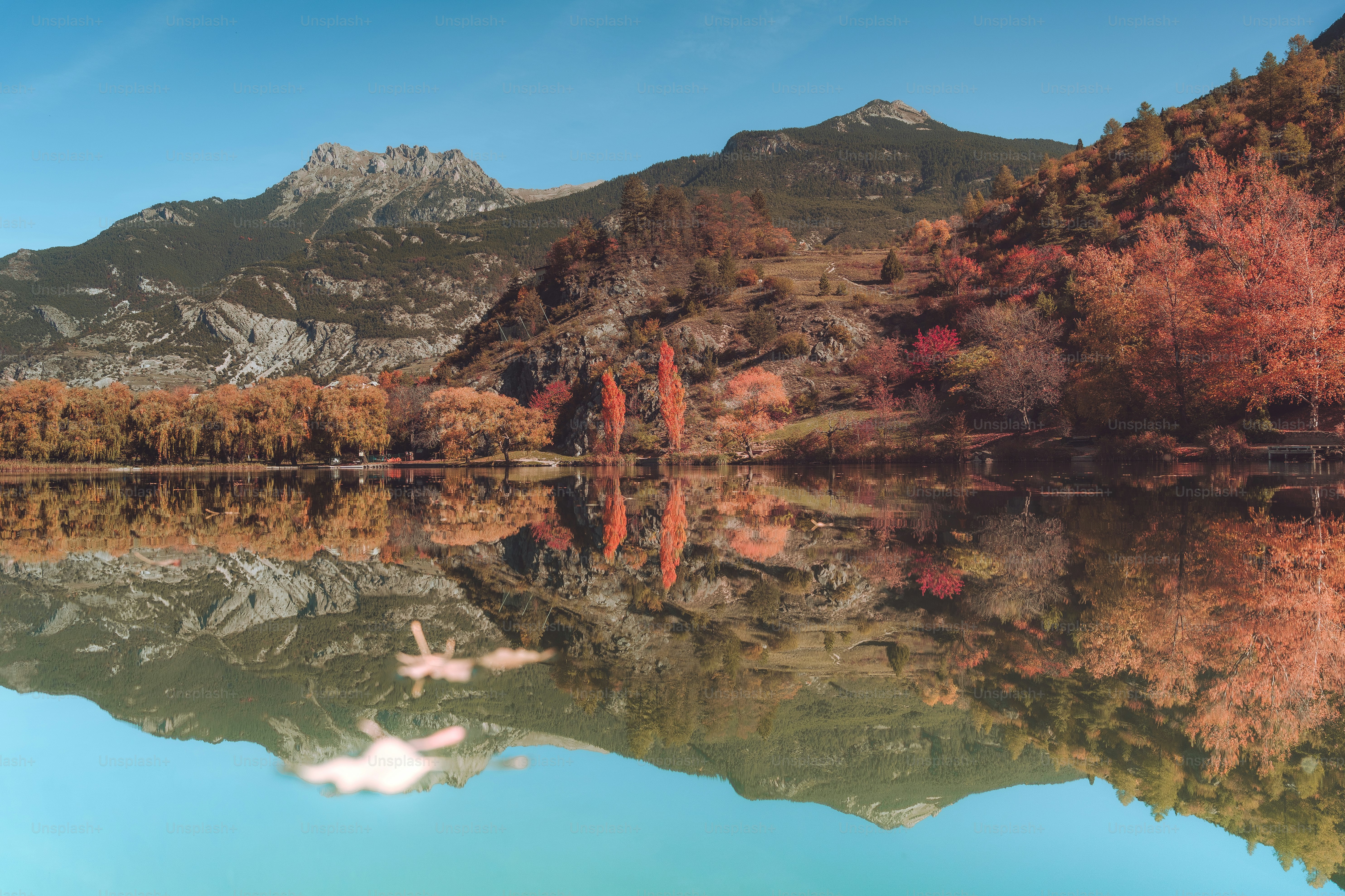 a mountain range is reflected in the still water of a lake