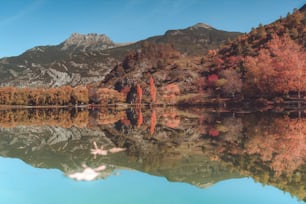 uma cordilheira se reflete na água parada de um lago