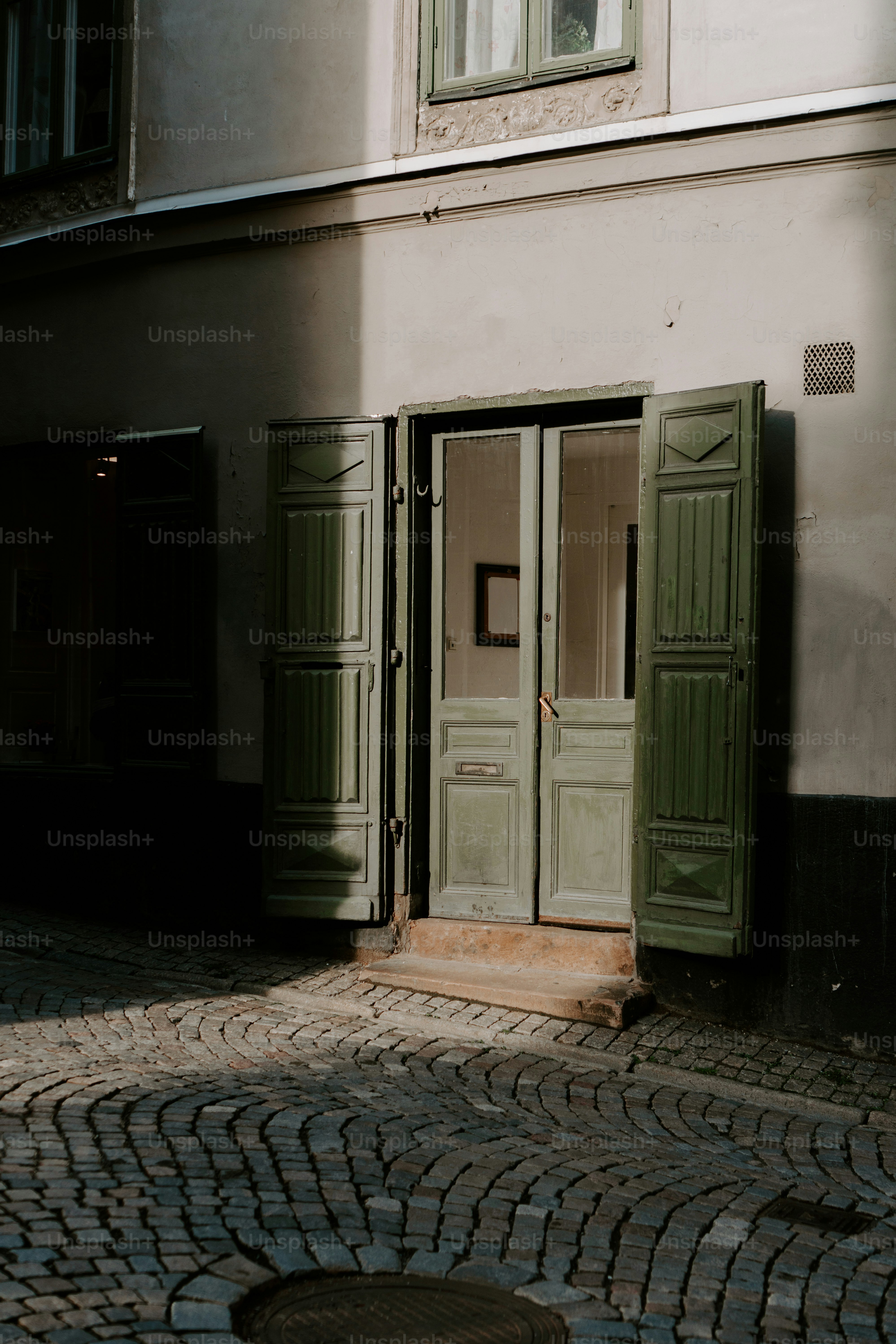 a building with two green doors and a fire hydrant