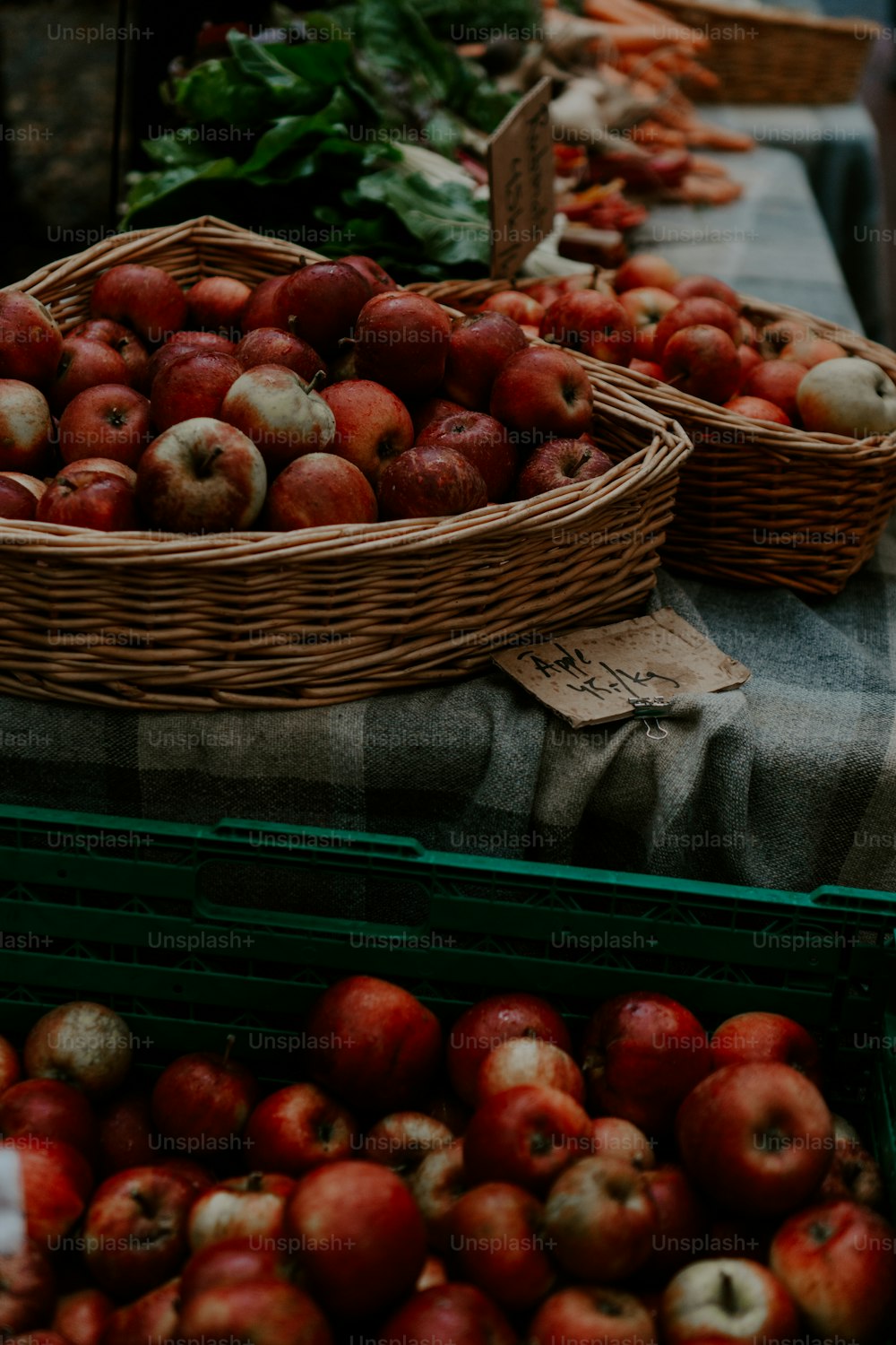 une table surmontée de paniers de pommes et de légumes