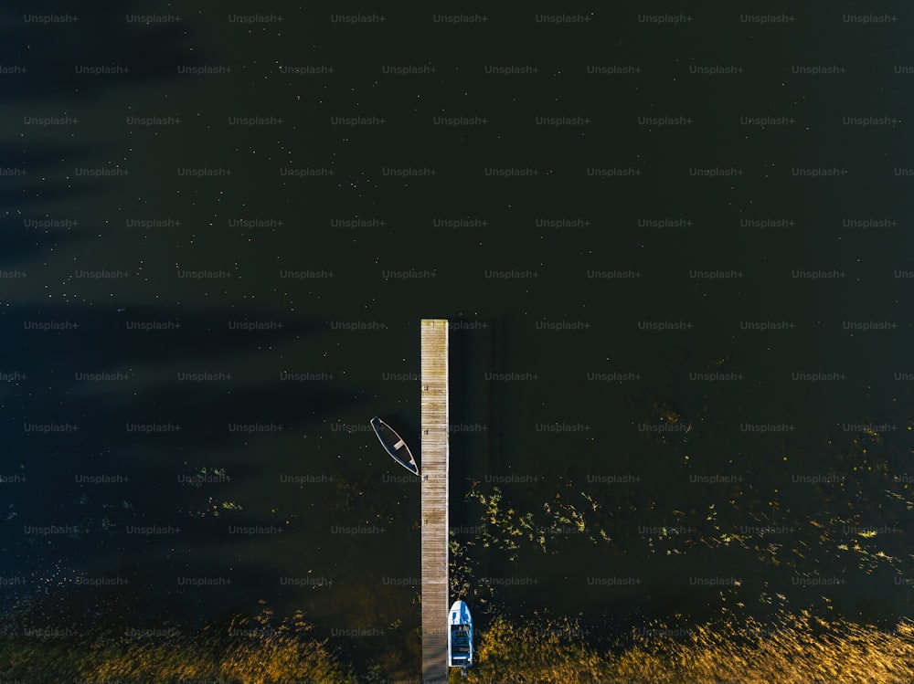 una persona in piedi su un molo vicino a uno specchio d'acqua