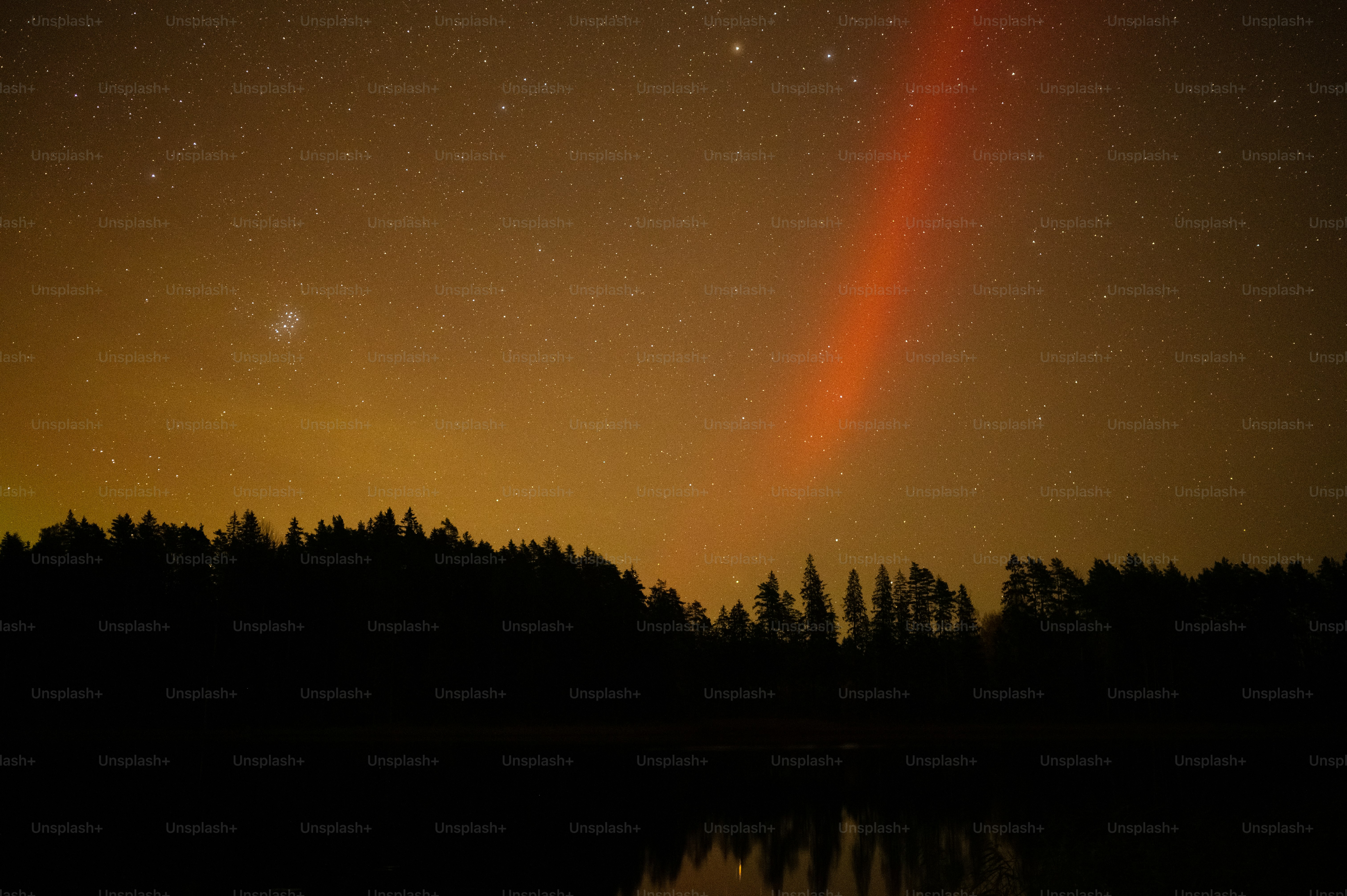 a bright orange light shines in the night sky over a lake