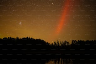 a bright orange light shines in the night sky over a lake