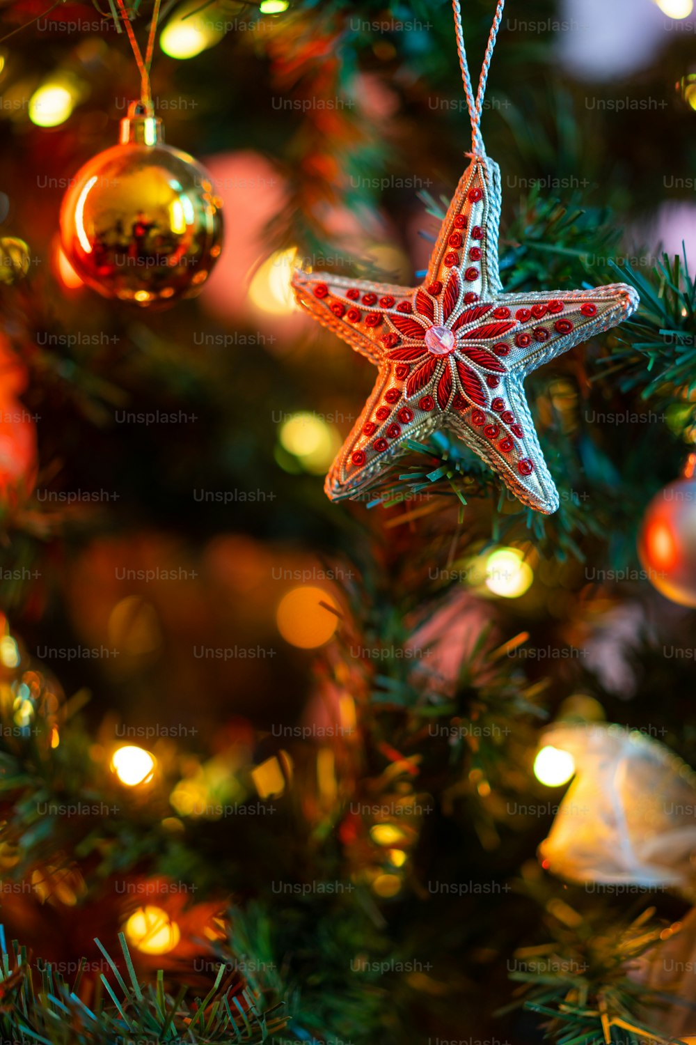 a red and white star ornament hanging from a christmas tree