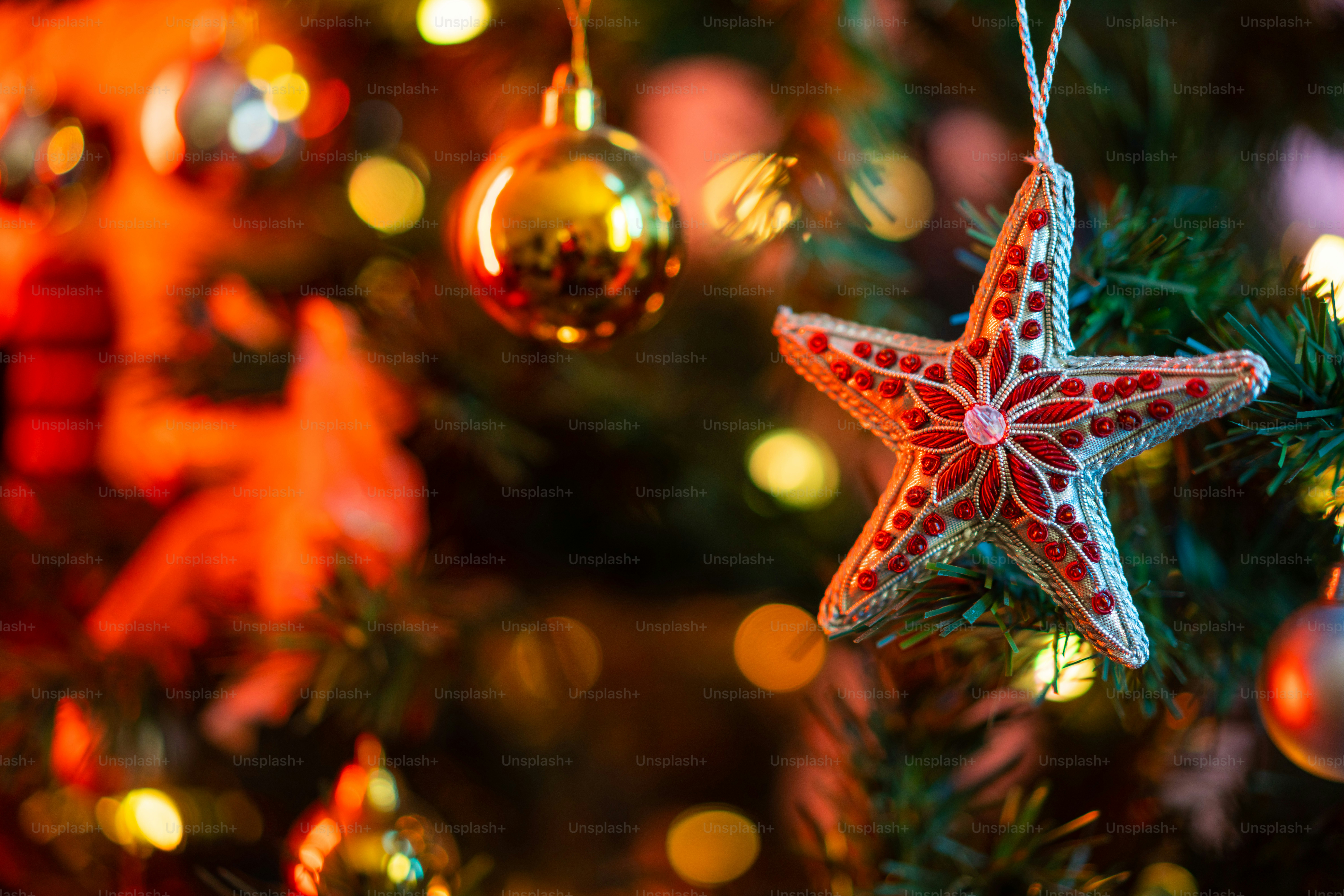 A star ornament hanging from a christmas tree photo – Decorations Image ...