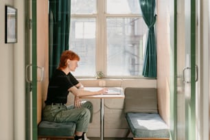 a woman sitting at a table in front of a window