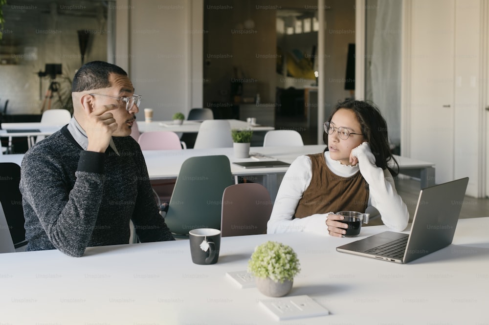 a man and woman sitting at a table with a laptop