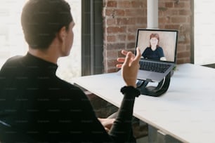 une personne assise à une table avec un ordinateur portable