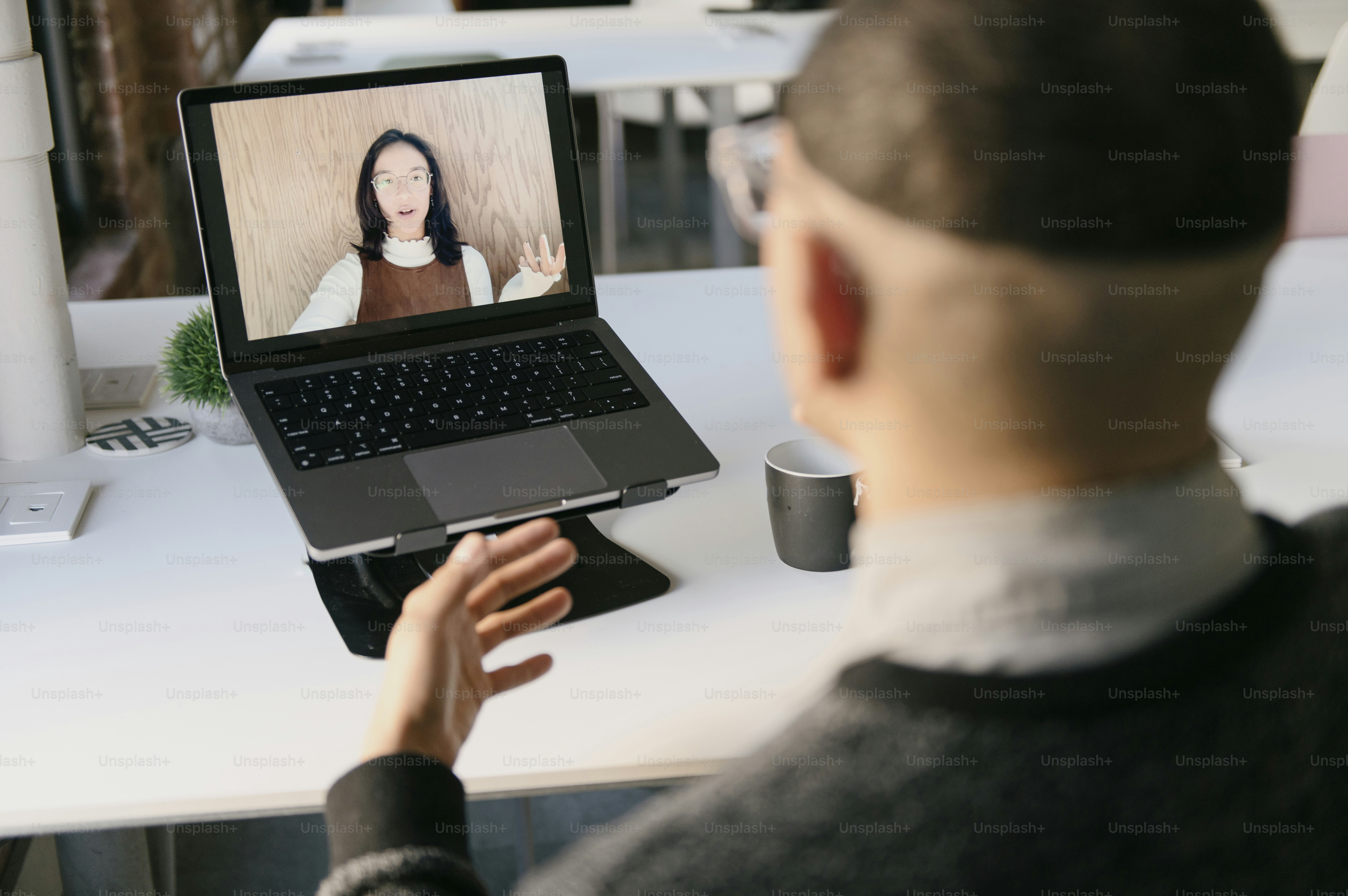 Ein Mann, der mit einem Laptop auf dem Schoß an einem Tisch sitzt