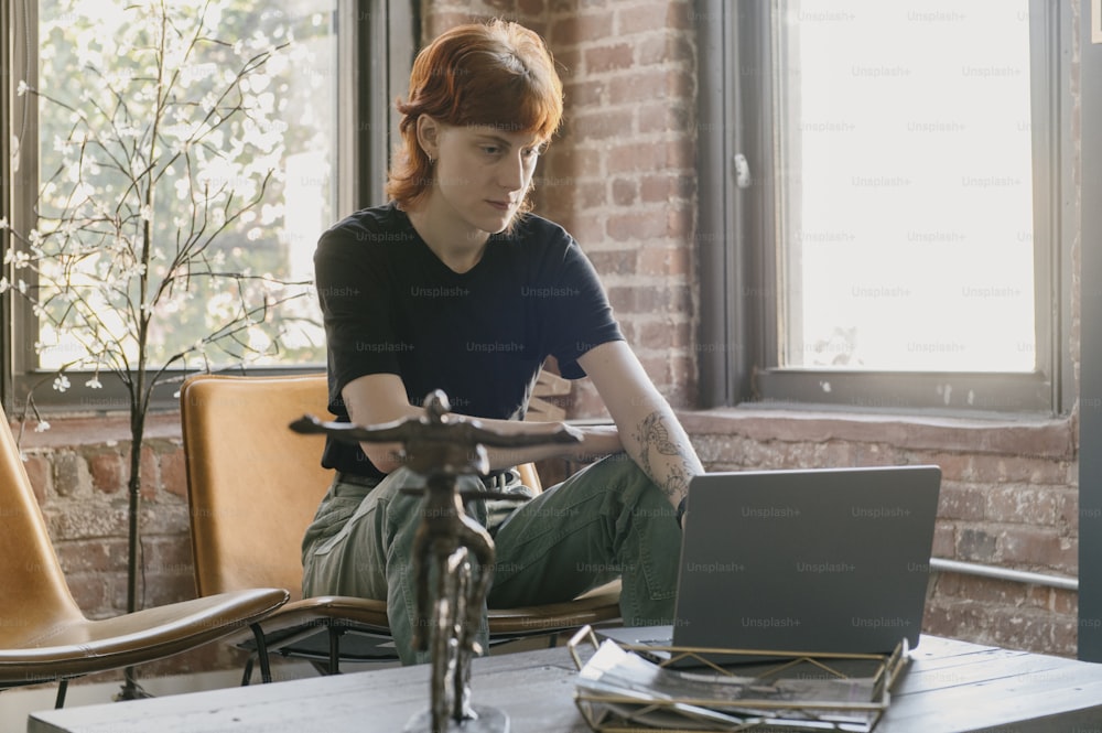 a woman sitting at a table using a laptop computer