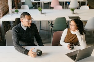 a man and woman sitting at a table with a laptop