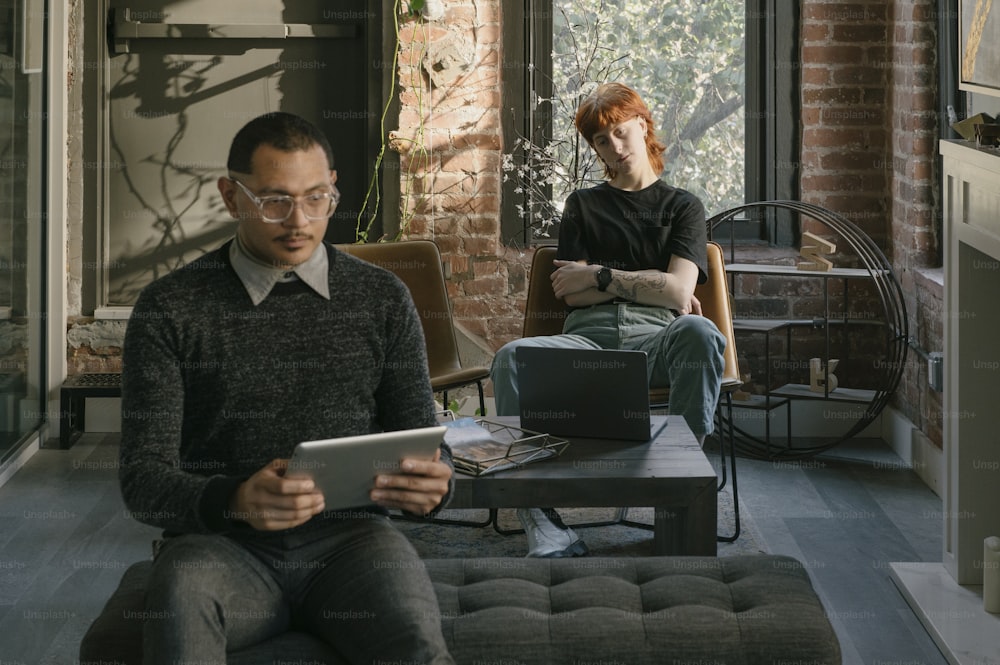 a man and a woman sitting on a couch looking at a tablet