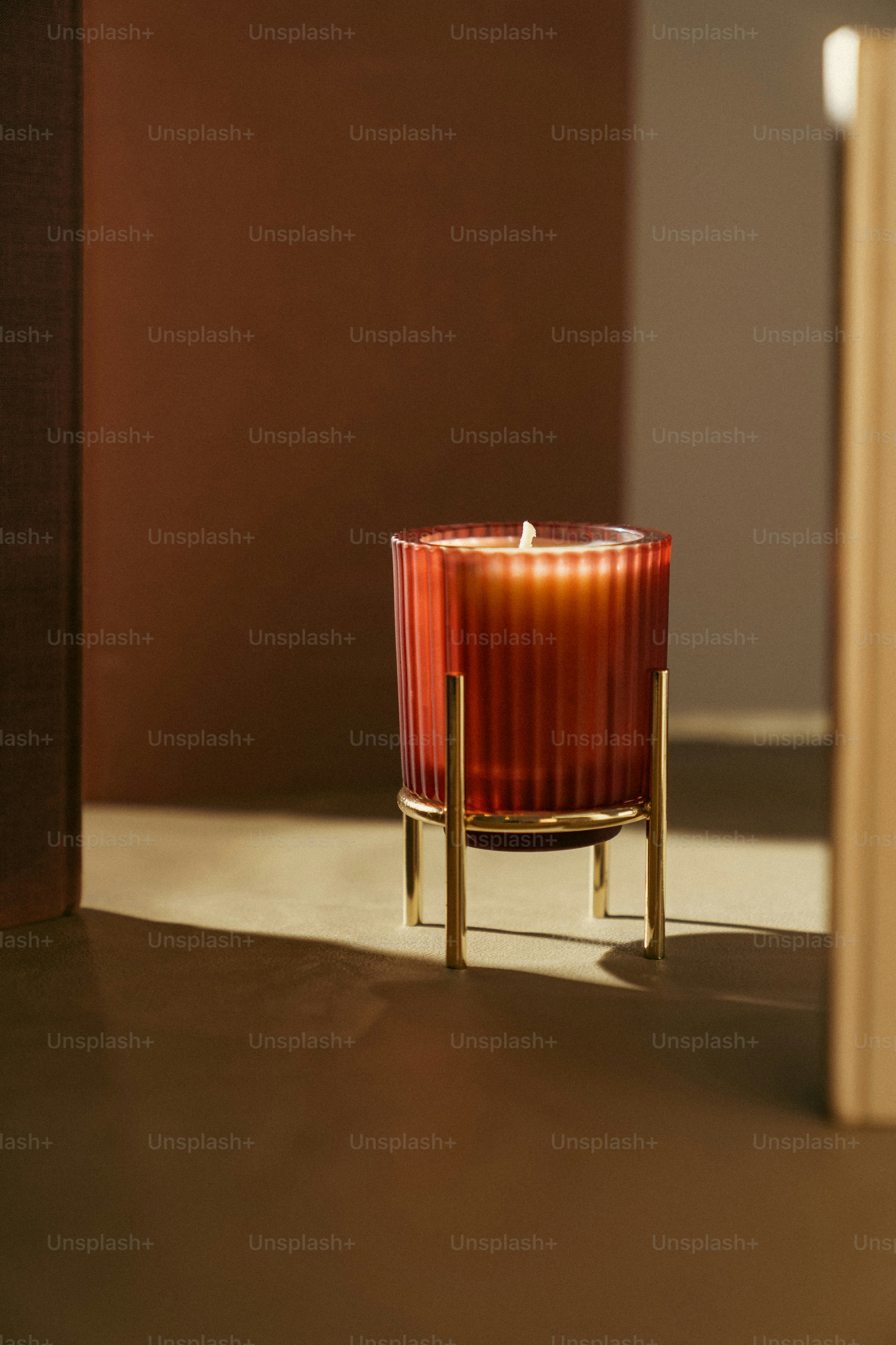 A red candle sitting on top of a table next to a book photo ...