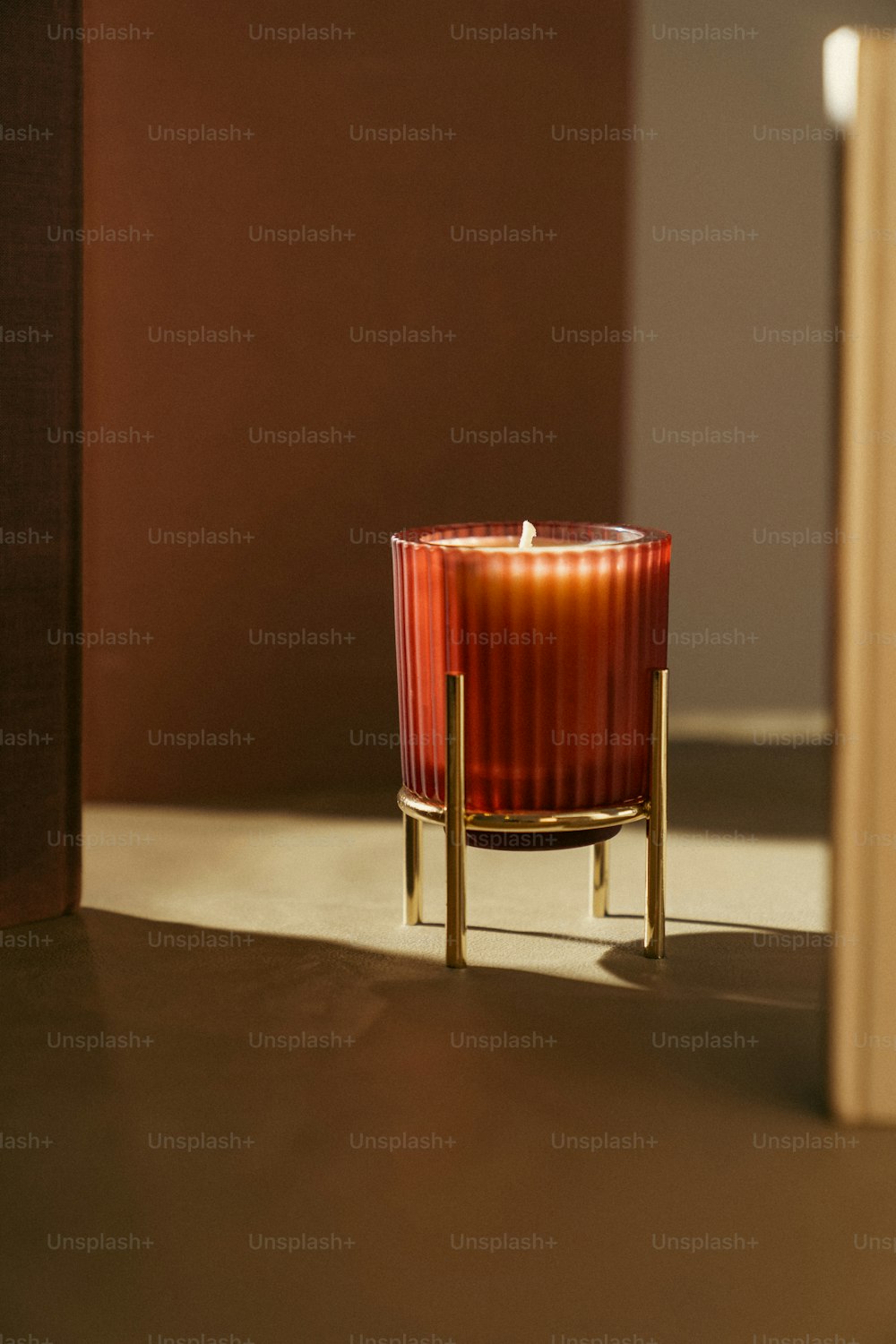 una candela rossa seduta sopra un tavolo accanto a un libro
