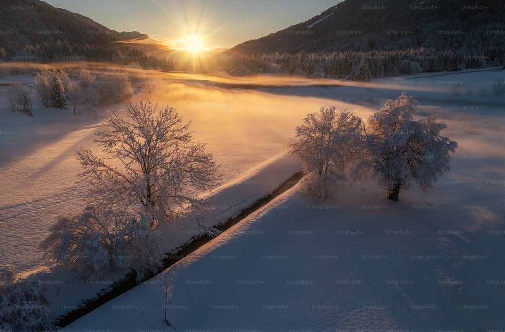 o sol está se pondo sobre uma paisagem nevada