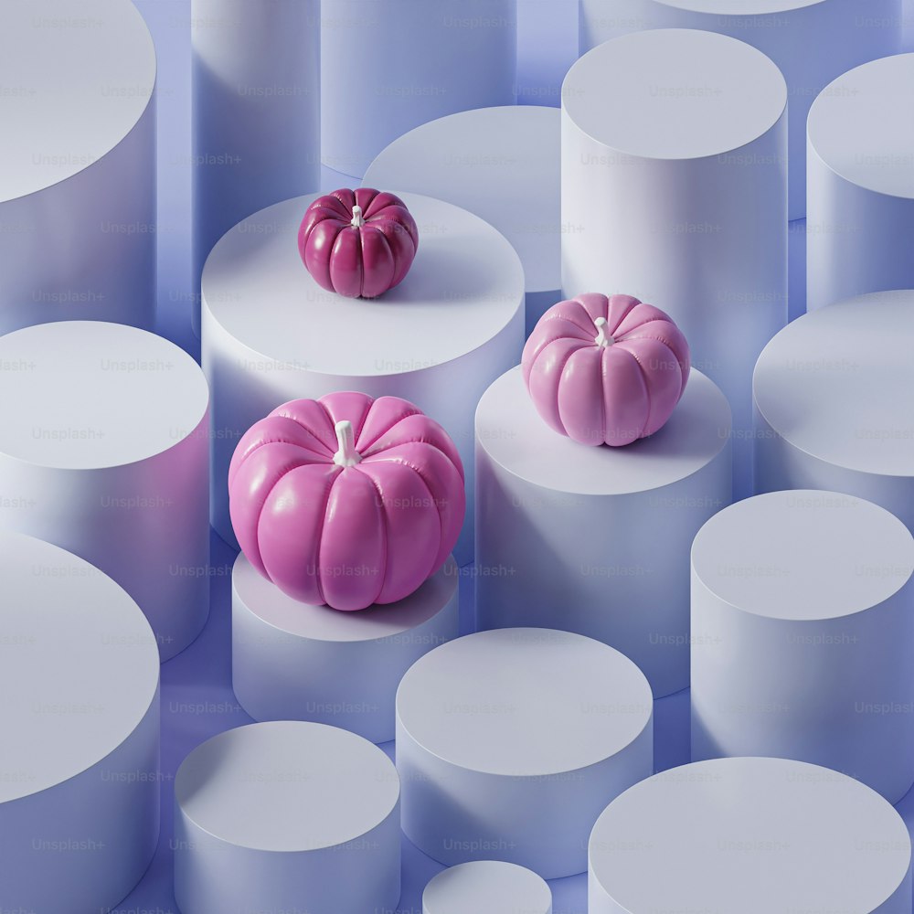 two pink pumpkins sitting on top of white pedestals