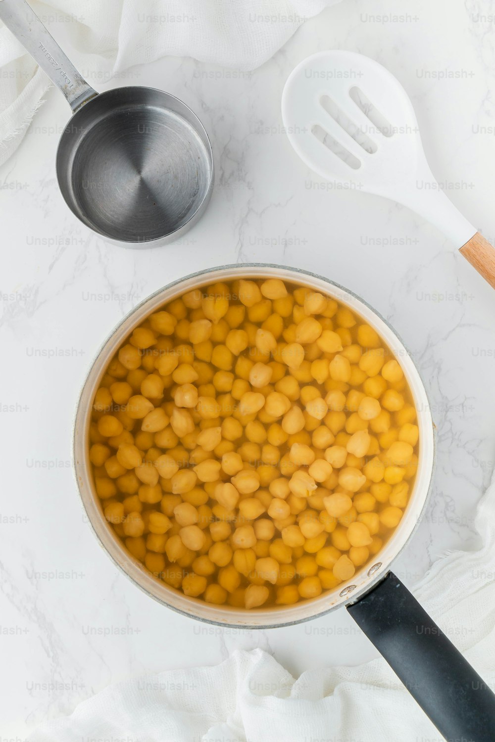 a pan filled with chickpeas next to a spatula