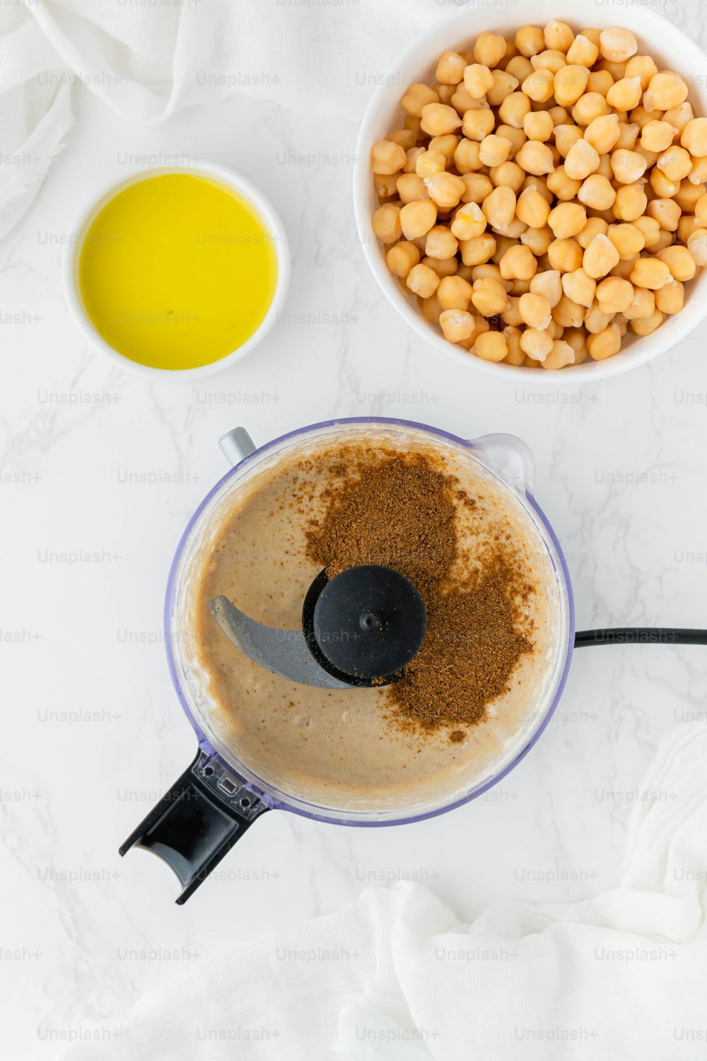 a blender filled with a mixture of ingredients next to a bowl of chickpe